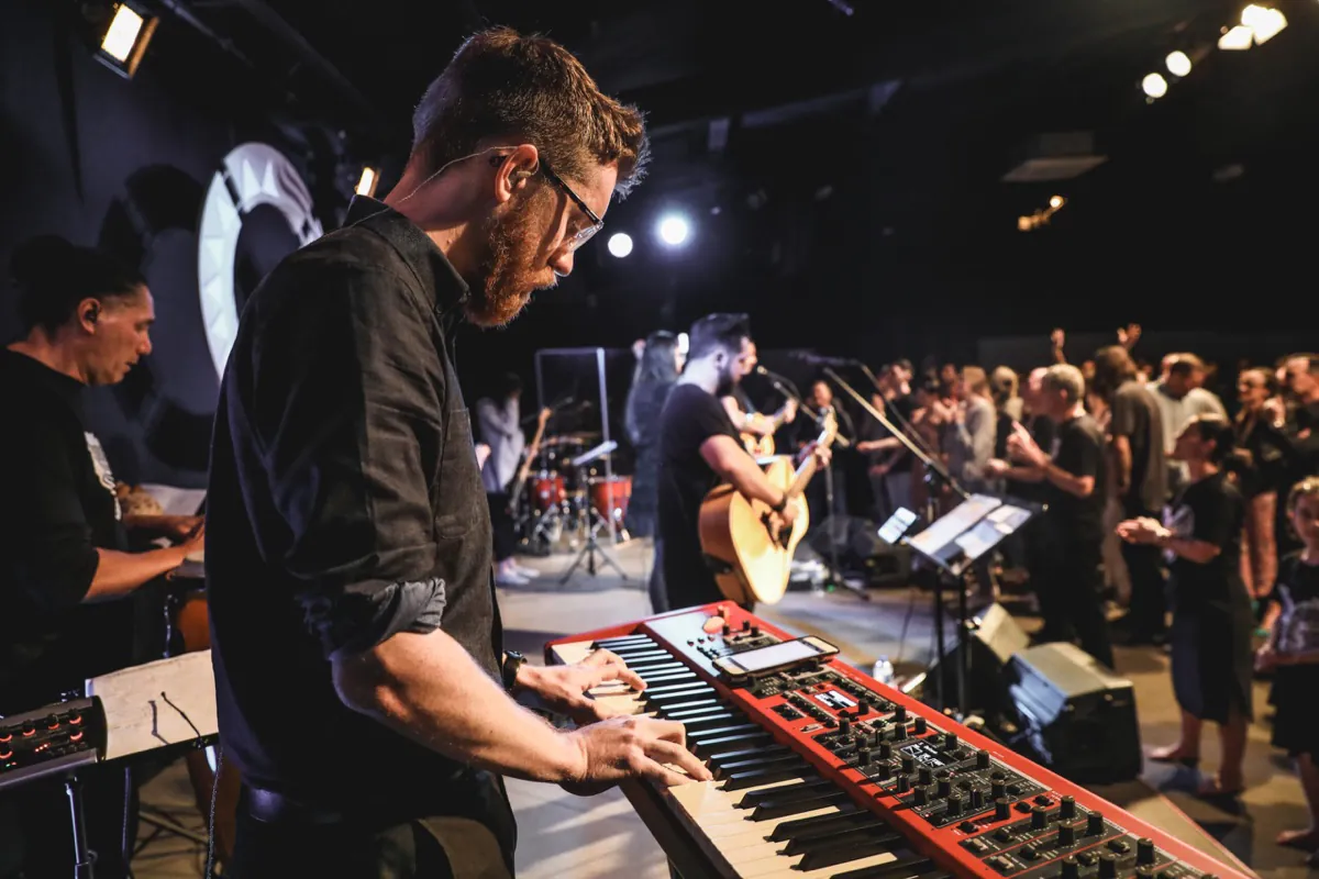 A keyboard player, worship band and congregation gathered for a Bethel NZ service.